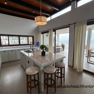 Kitchen opens to an expansive oceanfront patio with outdoor kitchen space